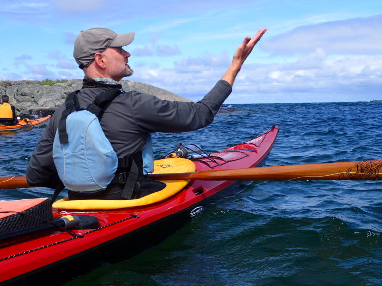A paddler mid-crossing pointing across the water