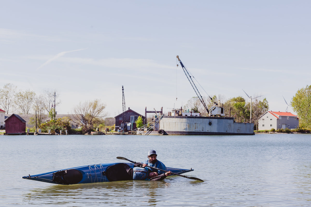 A sea kayaker practising rolling in calm harbour water